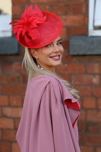 Woman in pink dress and red hat at Aintree Racecourse.