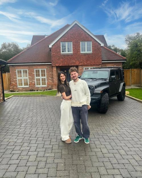 Conor Maynard and Charlotte Chilton standing in front of a house and car.