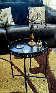 Black side table with coasters, candle holder, and reed diffuser.