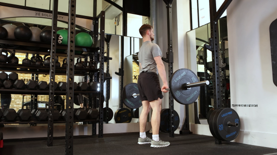 Man performing a barbell deadlift in a gym.