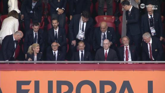 Group of people seated in stadium box seats.