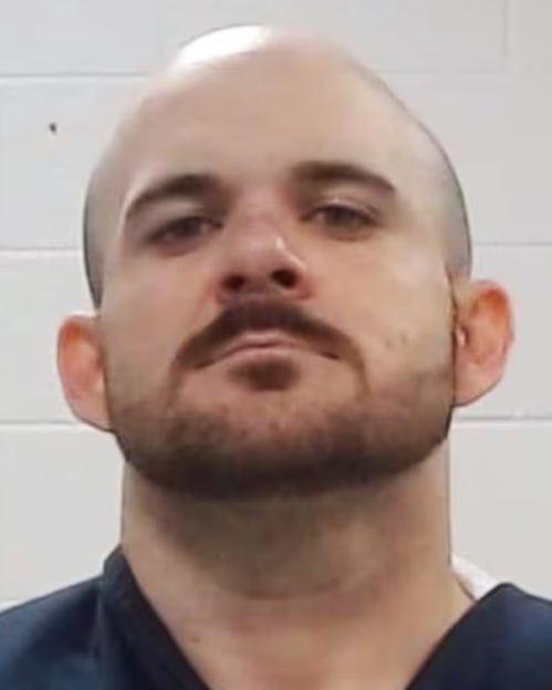 Mugshot of a bald man with a beard and mustache.