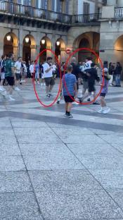 Video still showing Tottenham and Manchester United fans arguing and kicking a football at each other in a plaza.
