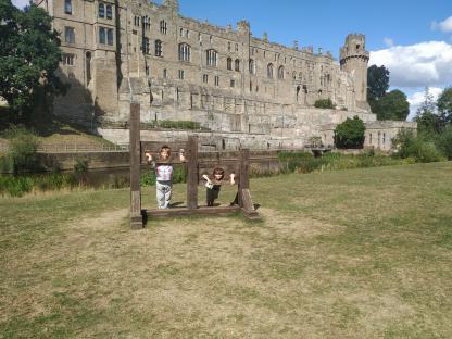 Two boys in a pillory in front of a castle.
