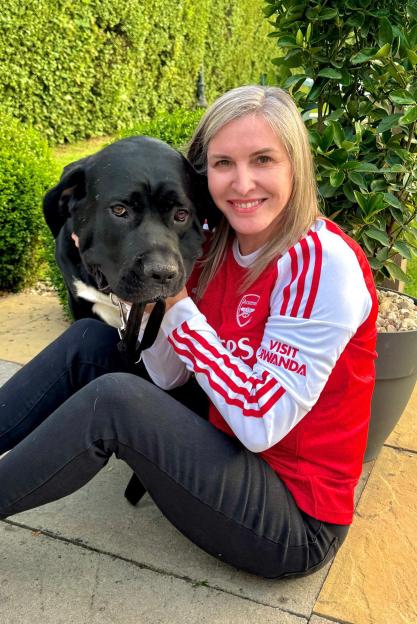 Leigh Cobb smiling while embracing her black dog.