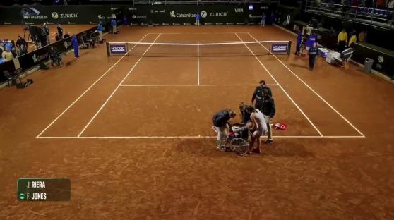 Fran Jones being helped into a wheelchair on a tennis court.