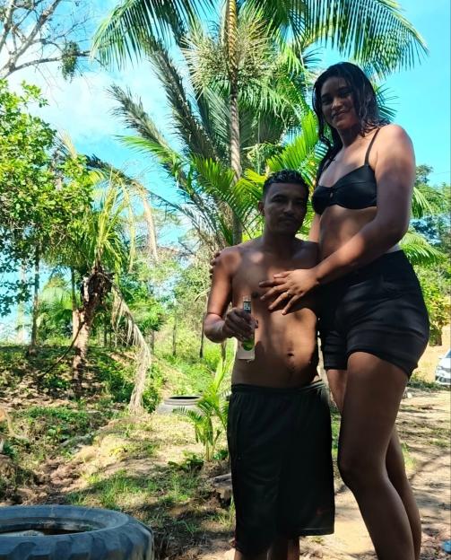A tall woman and a shorter man stand together outdoors.