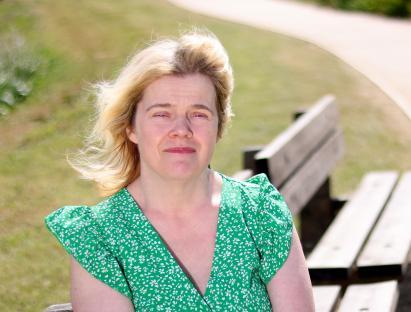 Louise Hopkins, sitting outdoors, wearing a green floral dress.
