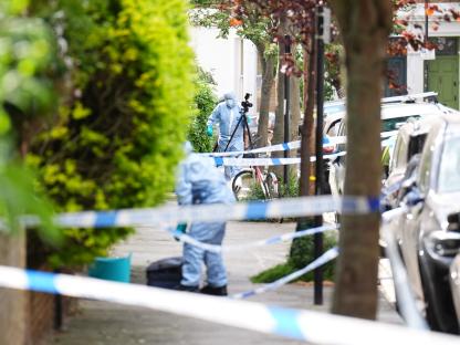 Forensic officers at a crime scene behind police tape.