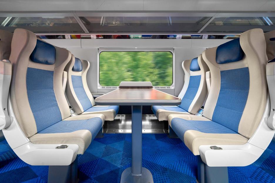 Interior of a modern train car with four seats and a table.