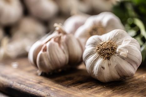 Organic garlic bulbs on a wooden cutting board.