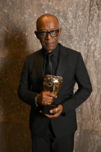 Lennie James holding a BAFTA award.