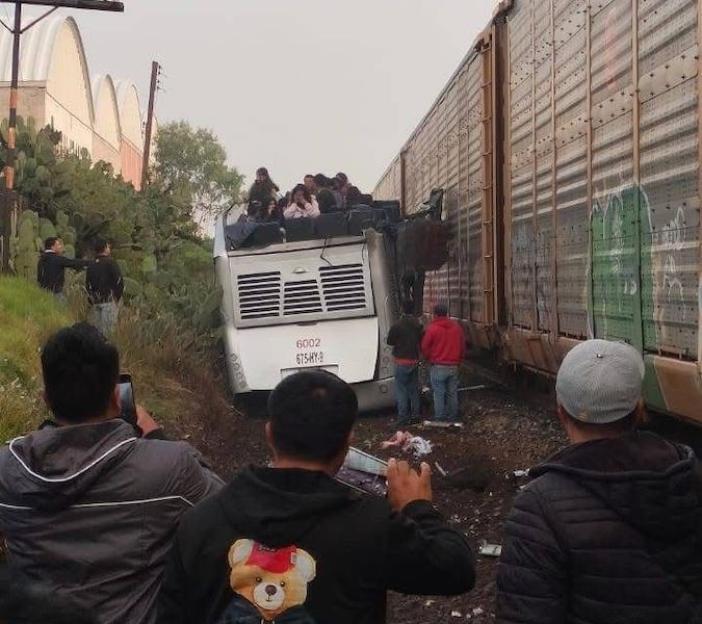Aftermath of a train colliding with a double-decker bus.