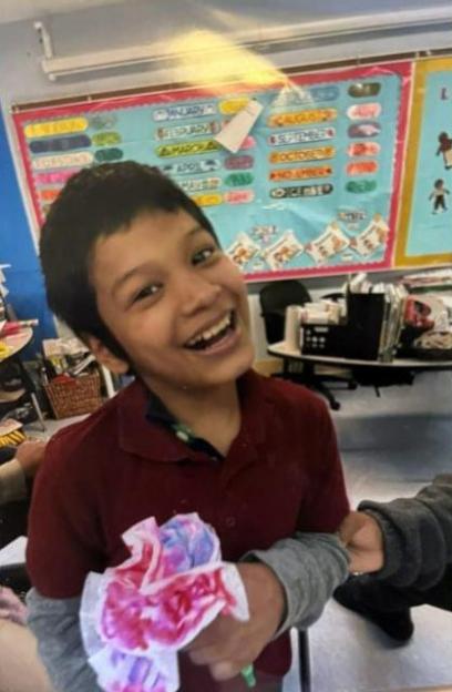 Photo of Bryan Vasquez, a smiling 12-year-old boy holding a painted flower.
