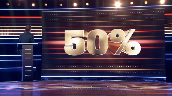 Screenshot of a game show set with a large 50% sign.