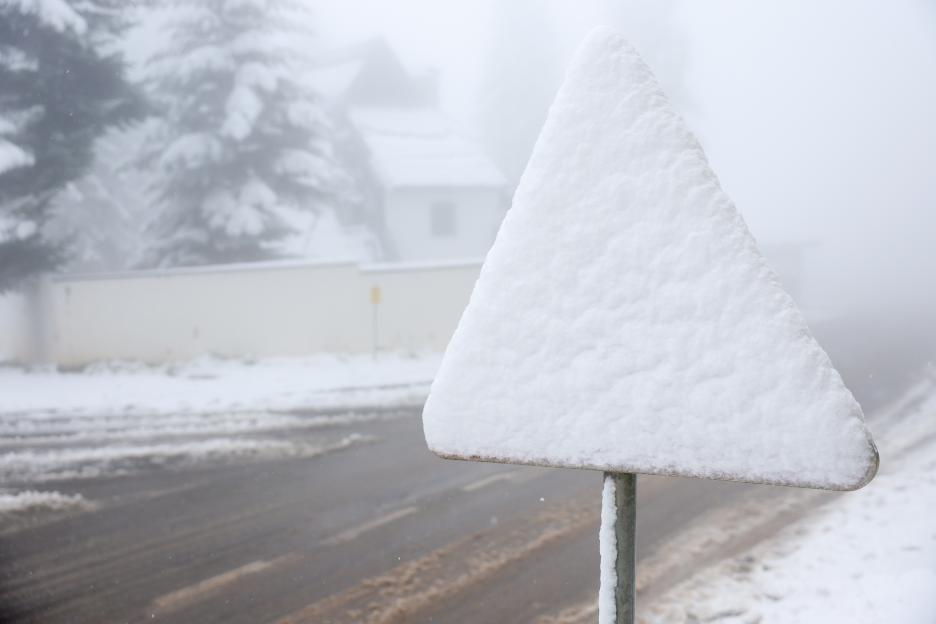 A triangular road sign is completely covered in snow during an unexpected snowfall on Mount Jahorina near Sarajevo, Bosnia.