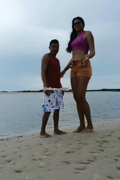 A tall woman and a shorter man standing on a beach.