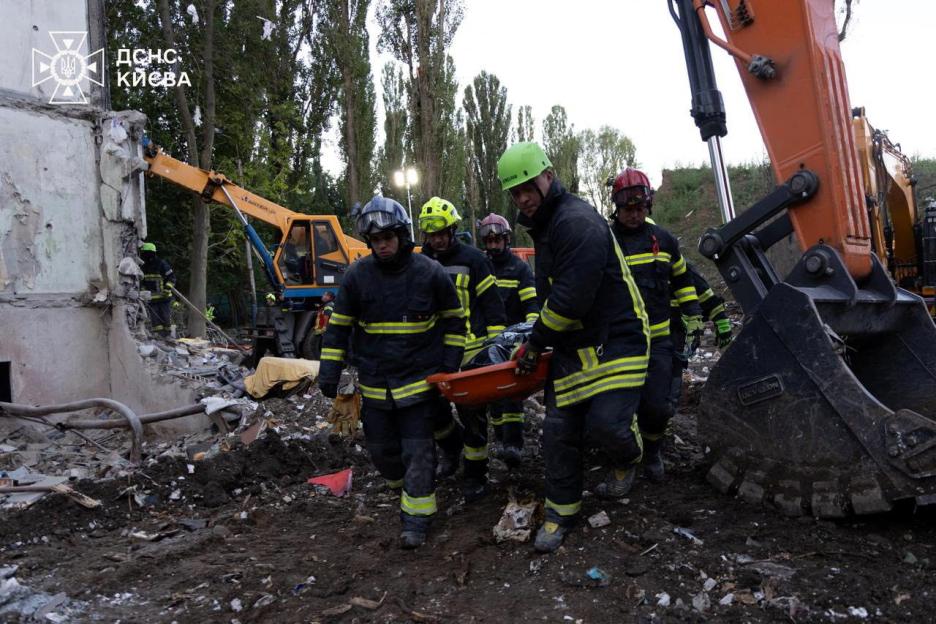 Rescuers carrying a body from a destroyed building.