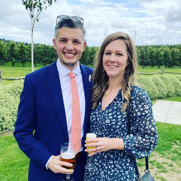 Couple standing outdoors holding drinks.