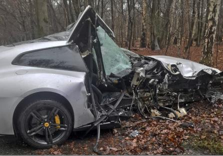 Severely damaged silver Ferrari in a forest.