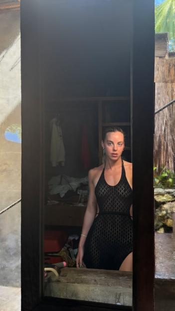 Keely Hodgkinson in a black crocheted halter-neck dress, posing in a doorway.