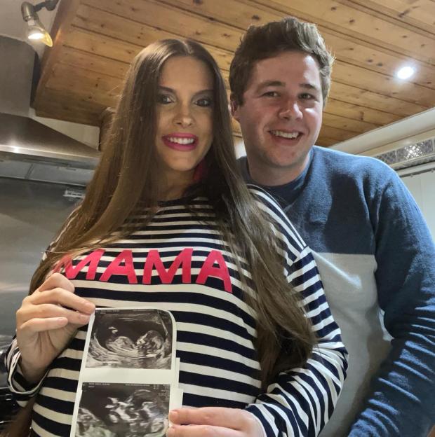 Frances and Oli holding an ultrasound image of their baby.