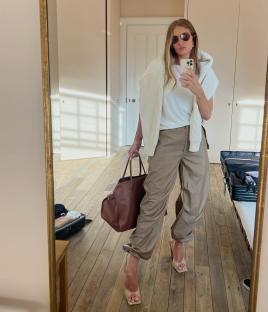 Woman taking a selfie in a beige outfit and brown handbag.