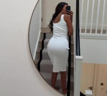 Woman in white dress reflected in a mirror.