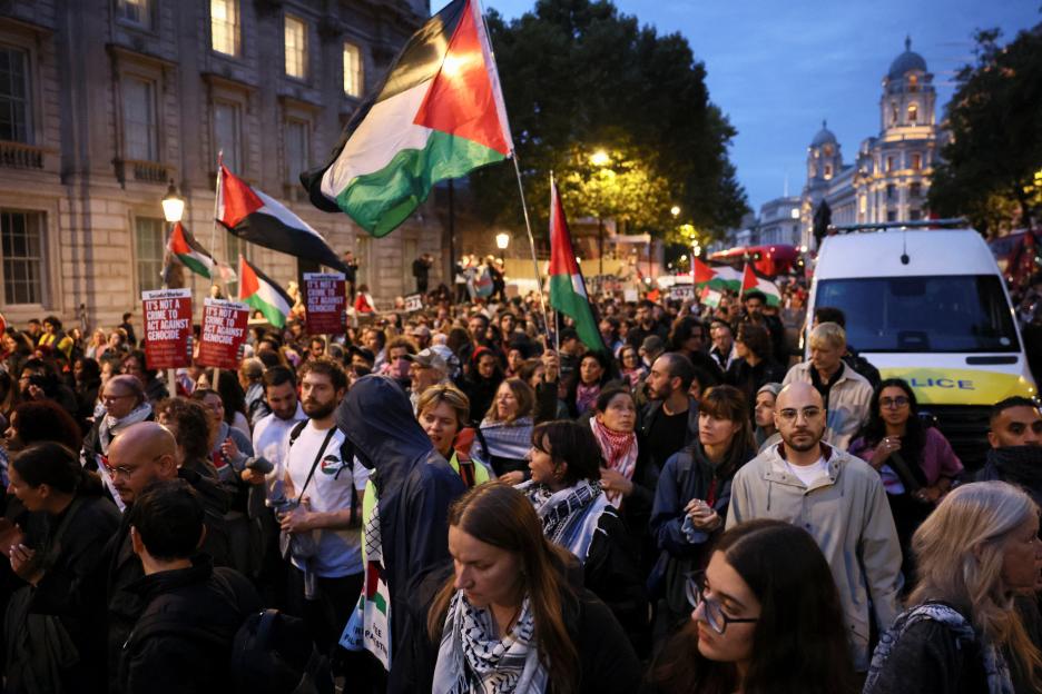People march in London holding Palestinian flags and signs stating "IT'S NOT A CRIME TO ACT AGAINST GENOCIDE" to protest and demand protection for the Global Sumud Flotilla.