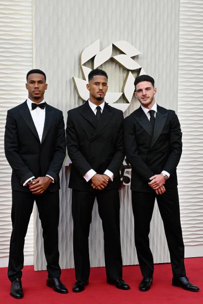 Three men in tuxedos at an awards ceremony.
