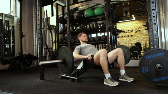 Man performing hip thrust exercise in a gym.