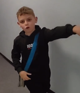 Boy in black hoodie gesturing.