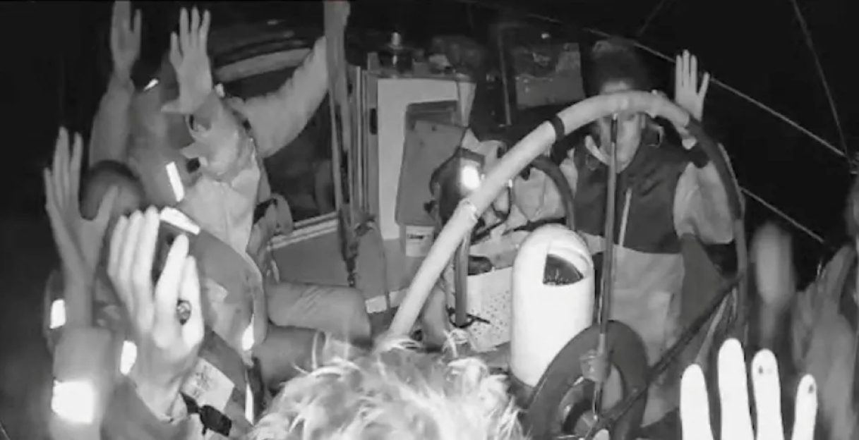People on a boat with hands raised in the air.