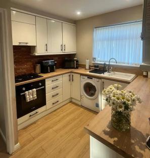 Small kitchen with white cabinets, brick backsplash, and wood-look flooring.