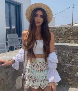Influencer Danielle Mansutti wearing a crochet skirt and straw hat.