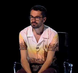 Man with glasses sitting in a chair.