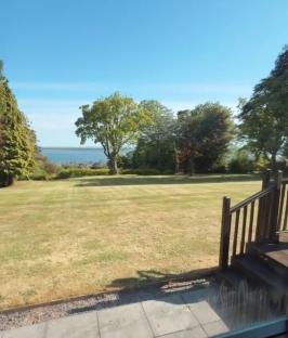 View from a window of a large lawn and body of water.
