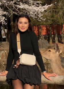 Woman in black dress petting a deer in Nara, Japan.