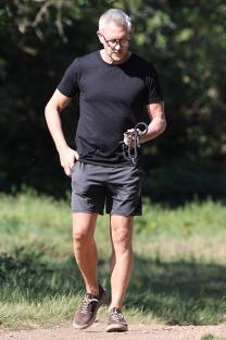 Gary Lineker walking in a park, holding a dog leash.
