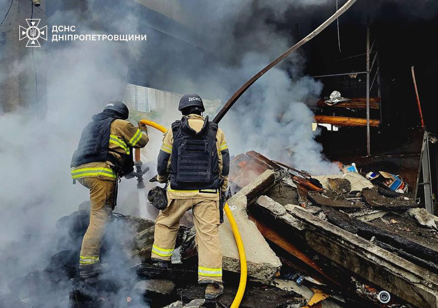 Firefighters battling a blaze amidst rubble.