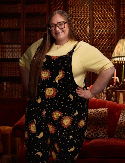 Woman wearing sun and moon overalls in a library setting.