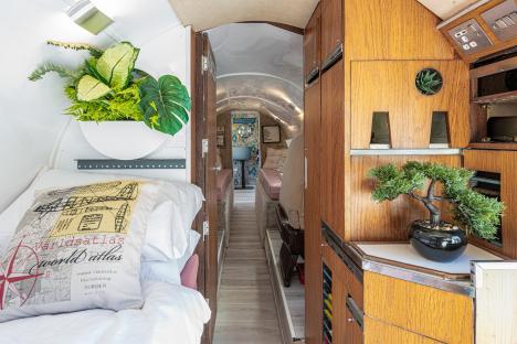 Interior of a converted private jet, showing a bed and hallway.