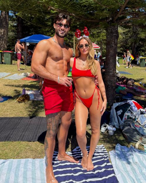 Couple in red swimwear on beach in Sydney, Australia.
