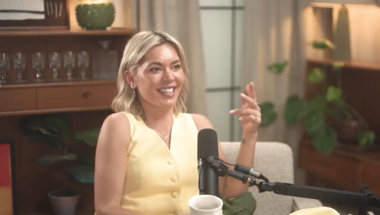 Woman in yellow dress sits and talks into a microphone.