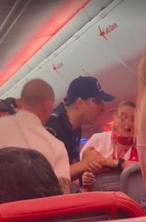 A man comforting a distressed woman on an airplane.