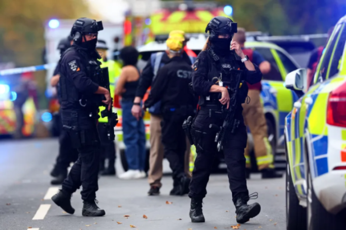 Police officers holding rifles at a crime scene.