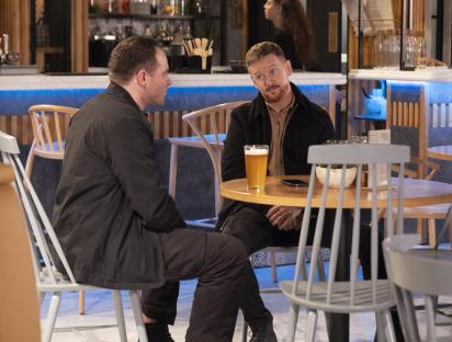 Two men having a drink and a conversation in a bistro.