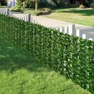 Artificial ivy covering a white picket fence.