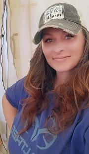 Woman wearing a baseball cap and blue shirt.