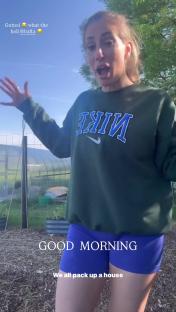 Woman in Nike sweatshirt reacting outdoors.